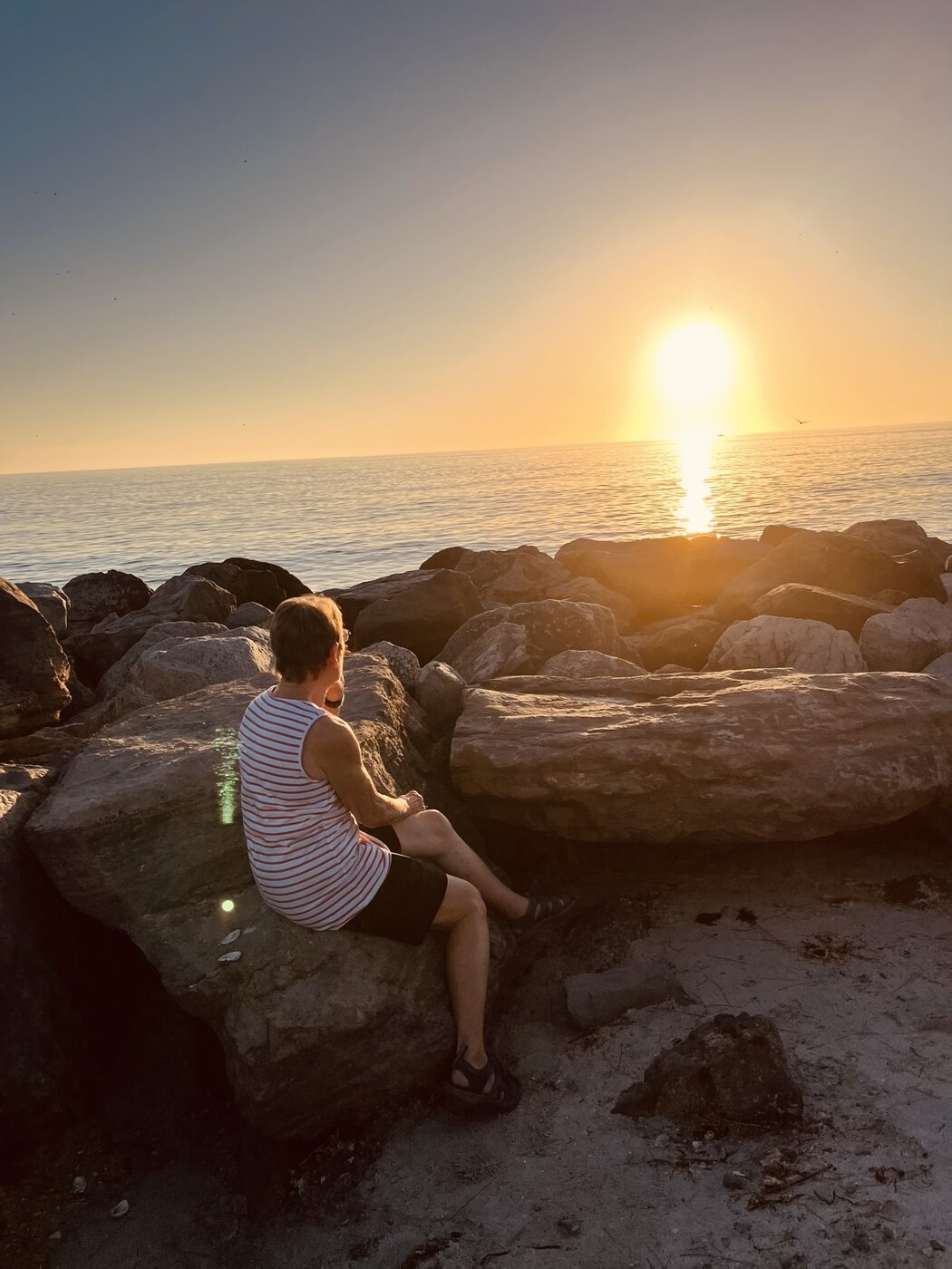 Trudy watching the sunset over the water from the rocks